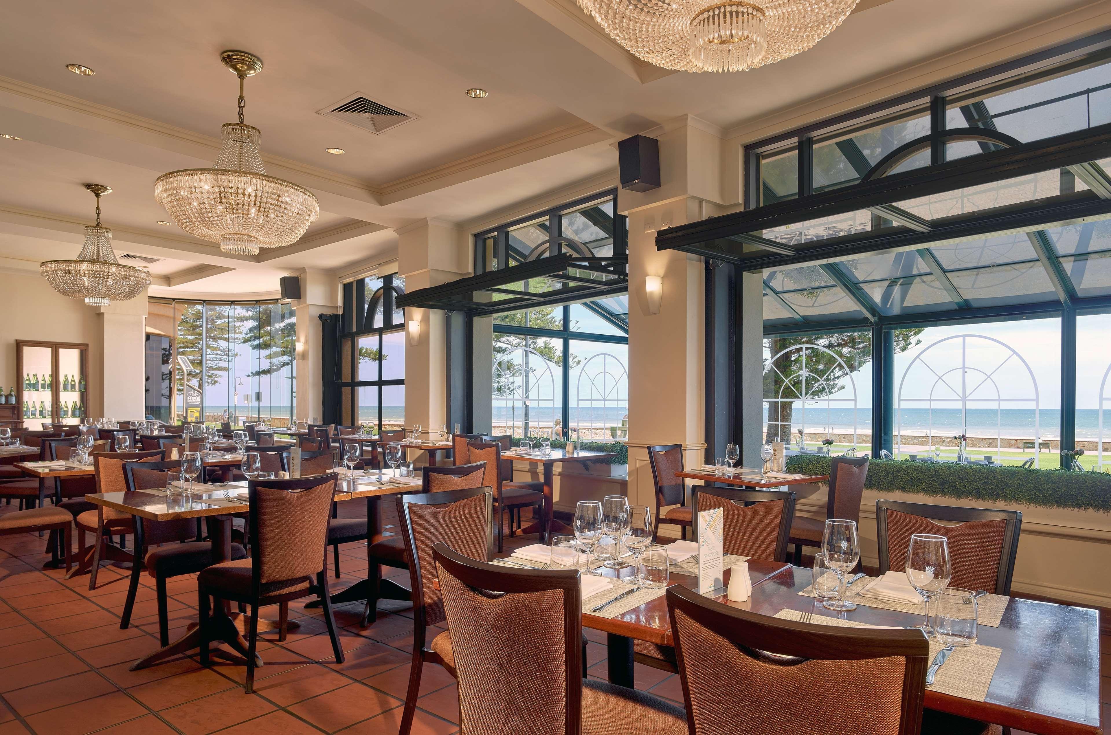 מלון גלנלג Stamford Grand Adelaide מראה חיצוני תמונה The photo shows the interior of a restaurant. It features several wooden tables set with glasses and utensils, suggesting it's ready for diners. The decor includes elegant chandeliers hanging from the ceiling, adding a touch of sophistication. Large 