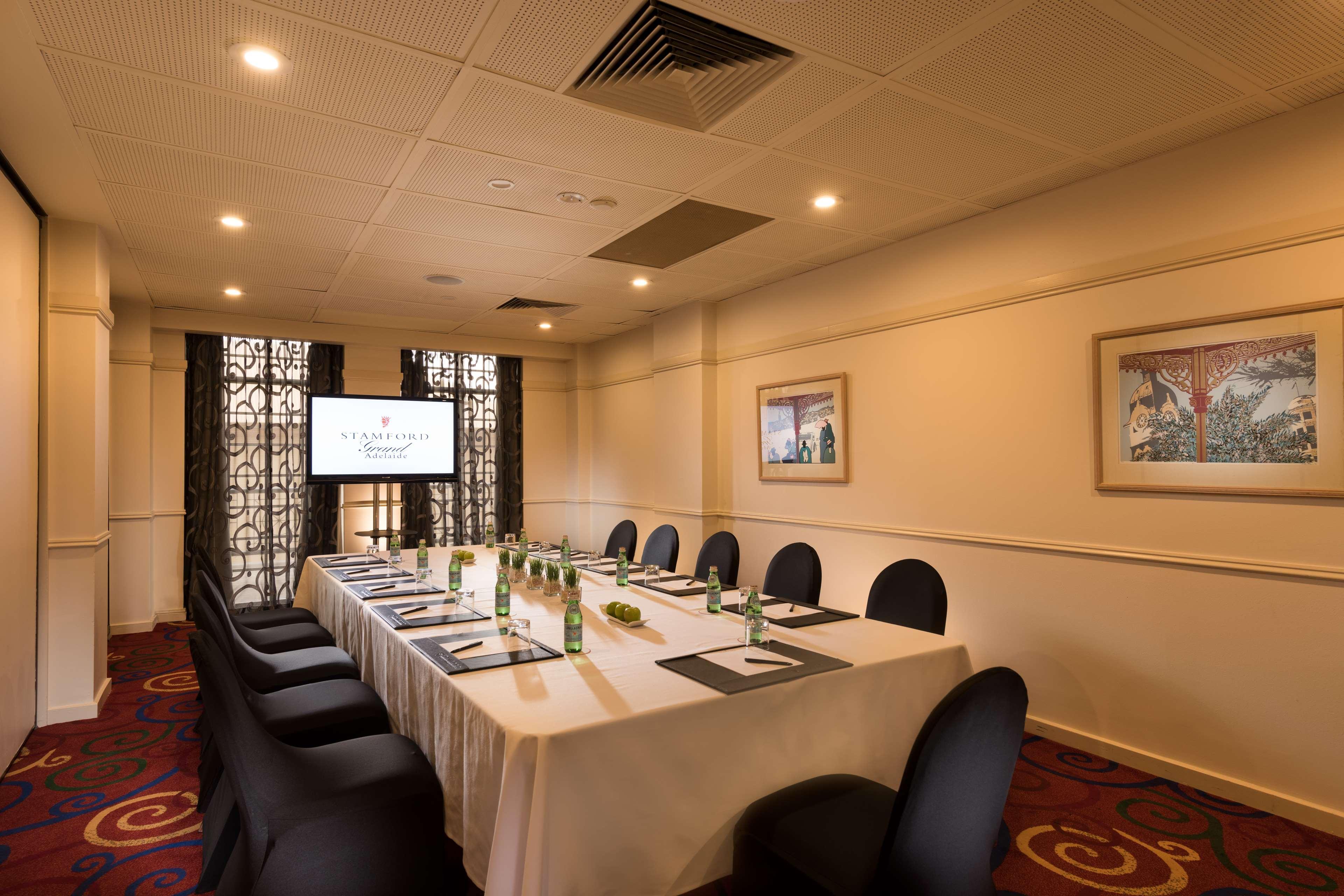 מלון גלנלג Stamford Grand Adelaide מראה חיצוני תמונה The photo shows a conference room with a long rectangular table set for a meeting. The table is covered with a white tablecloth and has several place settings, including notebooks, pens, and water bottles. There are black chairs around the table, and