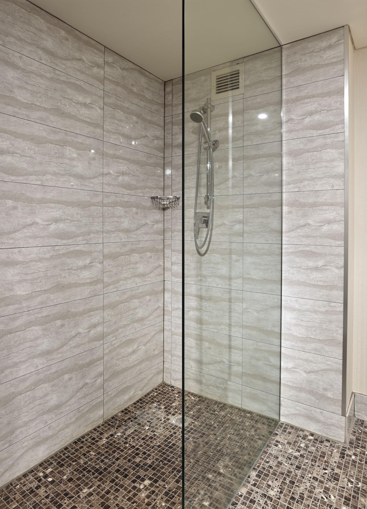 מלון גלנלג Stamford Grand Adelaide מראה חיצוני תמונה The photo shows a modern shower enclosure with a transparent glass door. The interior features tiled walls in a light, marble-like pattern, creating a clean and sleek look. There is a showerhead mounted on the wall, and the floor appears to be tiled 