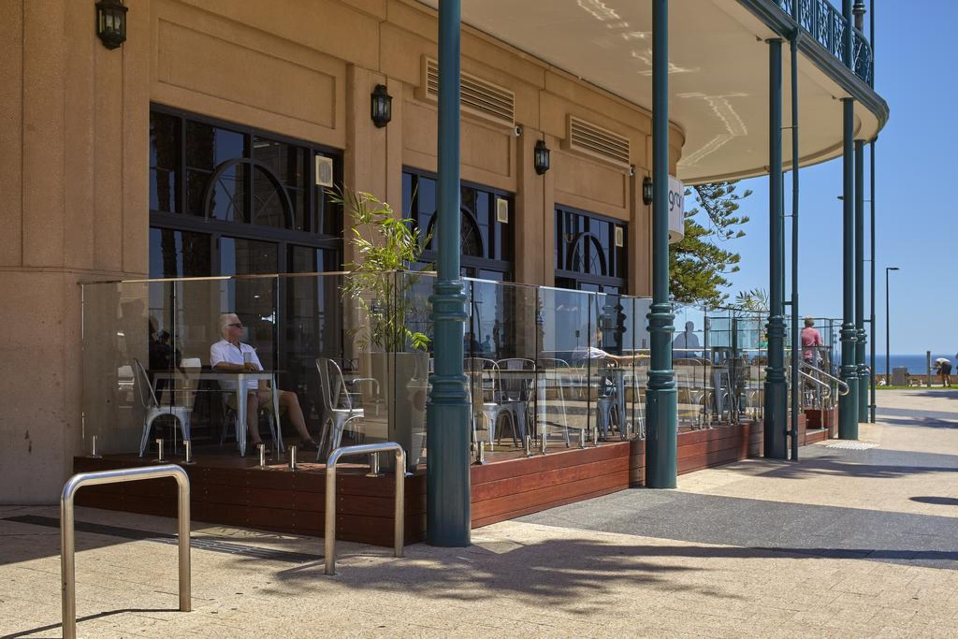 מלון גלנלג Stamford Grand Adelaide מראה חיצוני תמונה The photo shows the exterior of a cafe or restaurant with a large outdoor seating area. There are glass barriers around the seating, providing a view of the outside while maintaining a sense of enclosure. The building has a modern architectural style