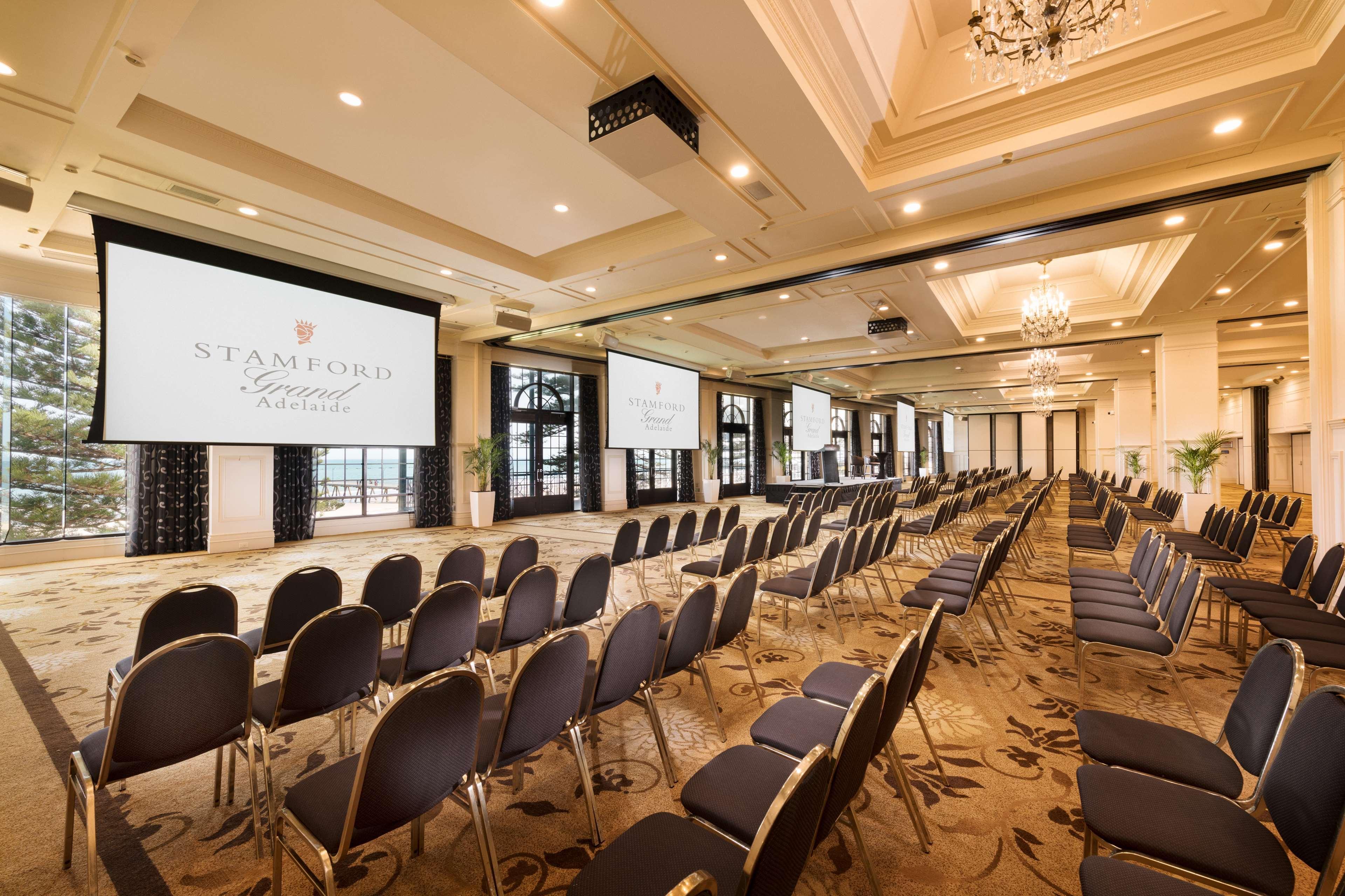 מלון גלנלג Stamford Grand Adelaide מראה חיצוני תמונה The photo shows a spacious event or conference room. There are rows of dark, upholstered chairs arranged facing two large screens. The room features elegant decor with soft lighting, a chandelier, and windows that allow natural light to filter in. Th