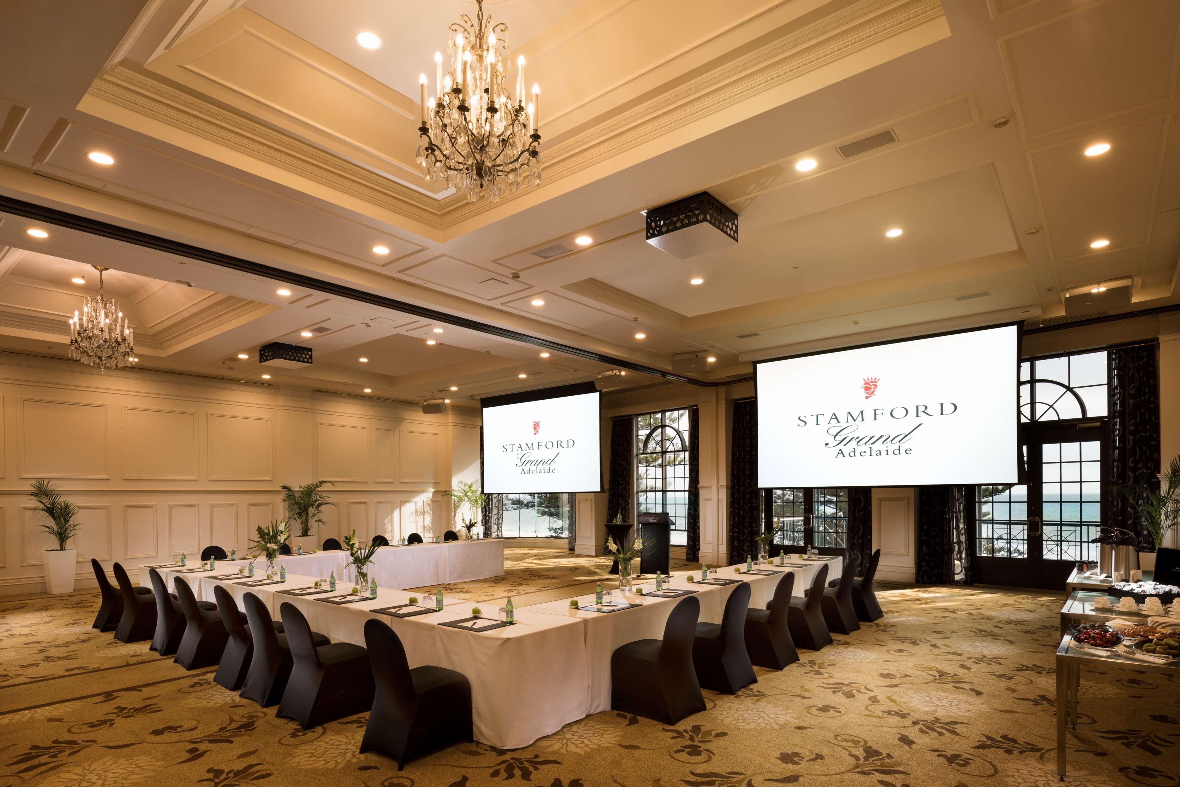 מלון גלנלג Stamford Grand Adelaide מראה חיצוני תמונה The photo shows a spacious and elegantly designed conference room. The room features a long table set for a meeting, surrounded by stylish chairs. Two large screens are positioned at the front, displaying the logo "Stamford Grand Melbourne." The ceil