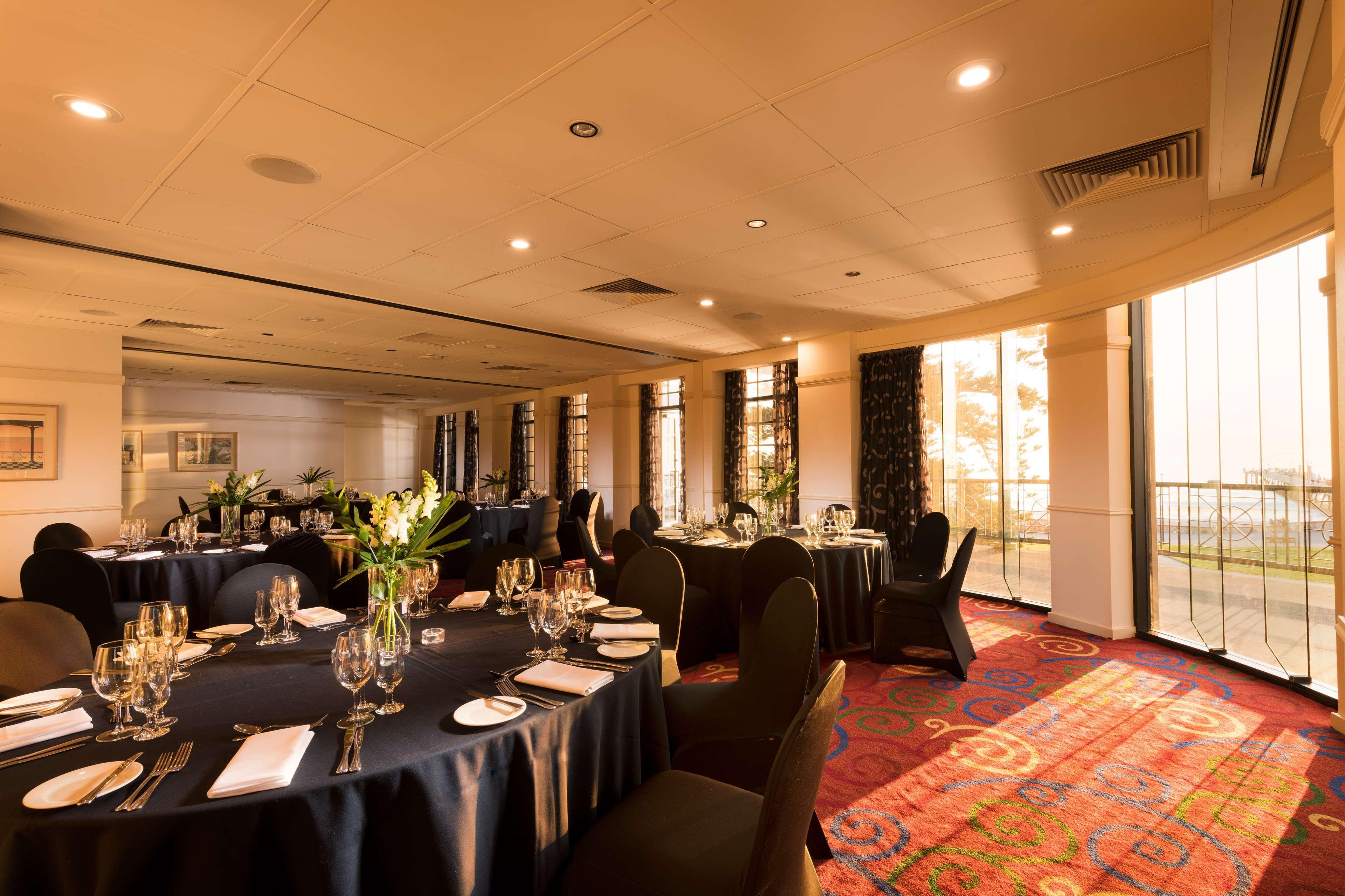מלון גלנלג Stamford Grand Adelaide מראה חיצוני תמונה The photo shows a well-decorated event space or dining area. There are several round tables draped in dark tablecloths, each set with elegant dinnerware, including glasses and cutlery. The room features large windows that allow natural light to flood