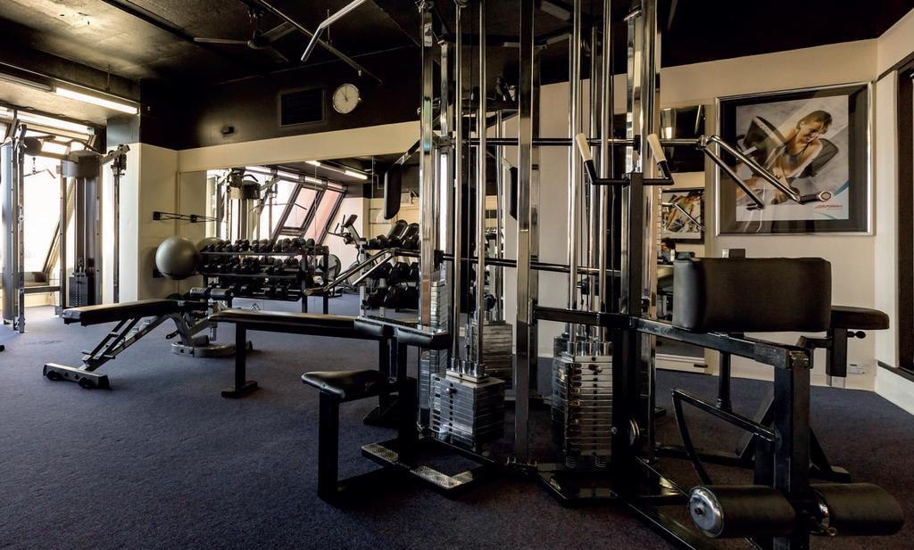 מלון גלנלג Stamford Grand Adelaide מראה חיצוני תמונה The photo shows a gym interior with several pieces of exercise equipment. In the foreground, there is a multi-station machine that features various pulleys and weights. To the side, there are benches and free weights, including dumbbells. The gym has
